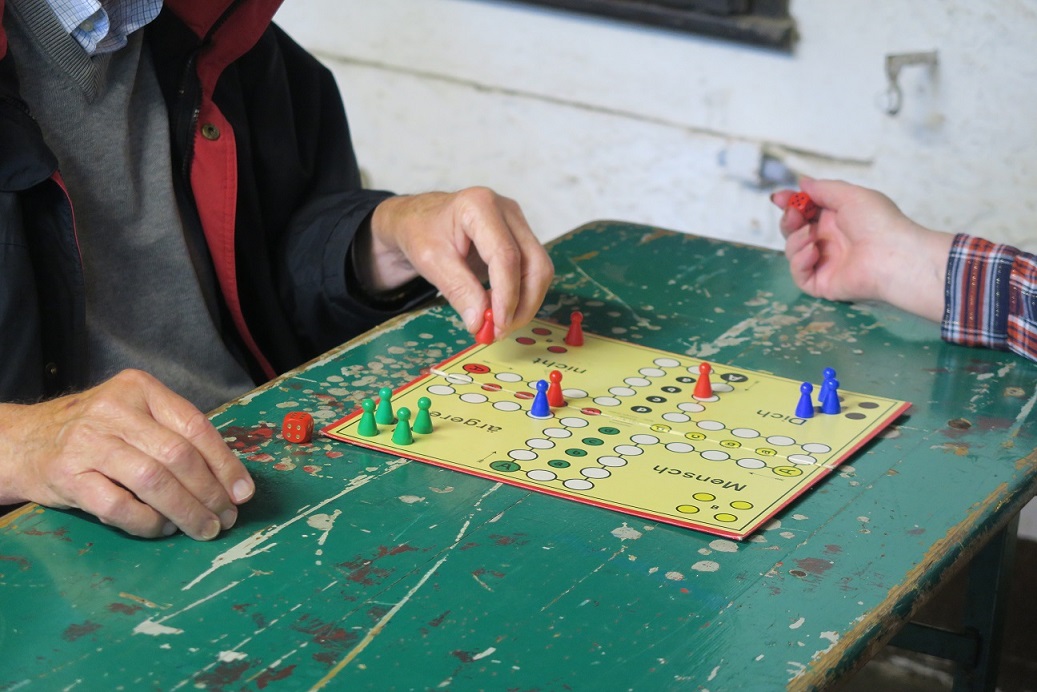Zwei Menschen spielen das Brettspiel Mensch ärgere dich nicht.