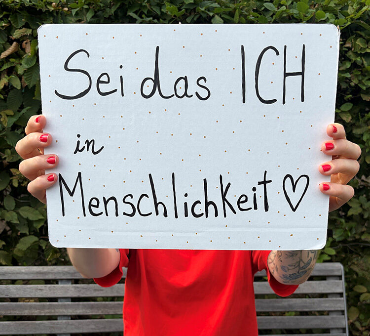 Mitarbeiter der AWO hält ein Schild mit der Aufschrift "Sei das Ich in Menschlichkeit"